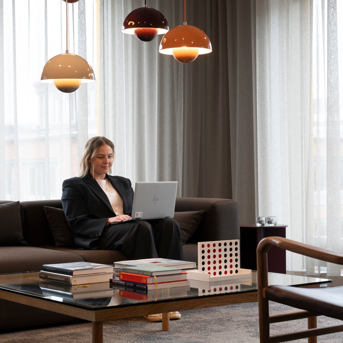 En kvinna sitter i en soffa med en bärbar dator.