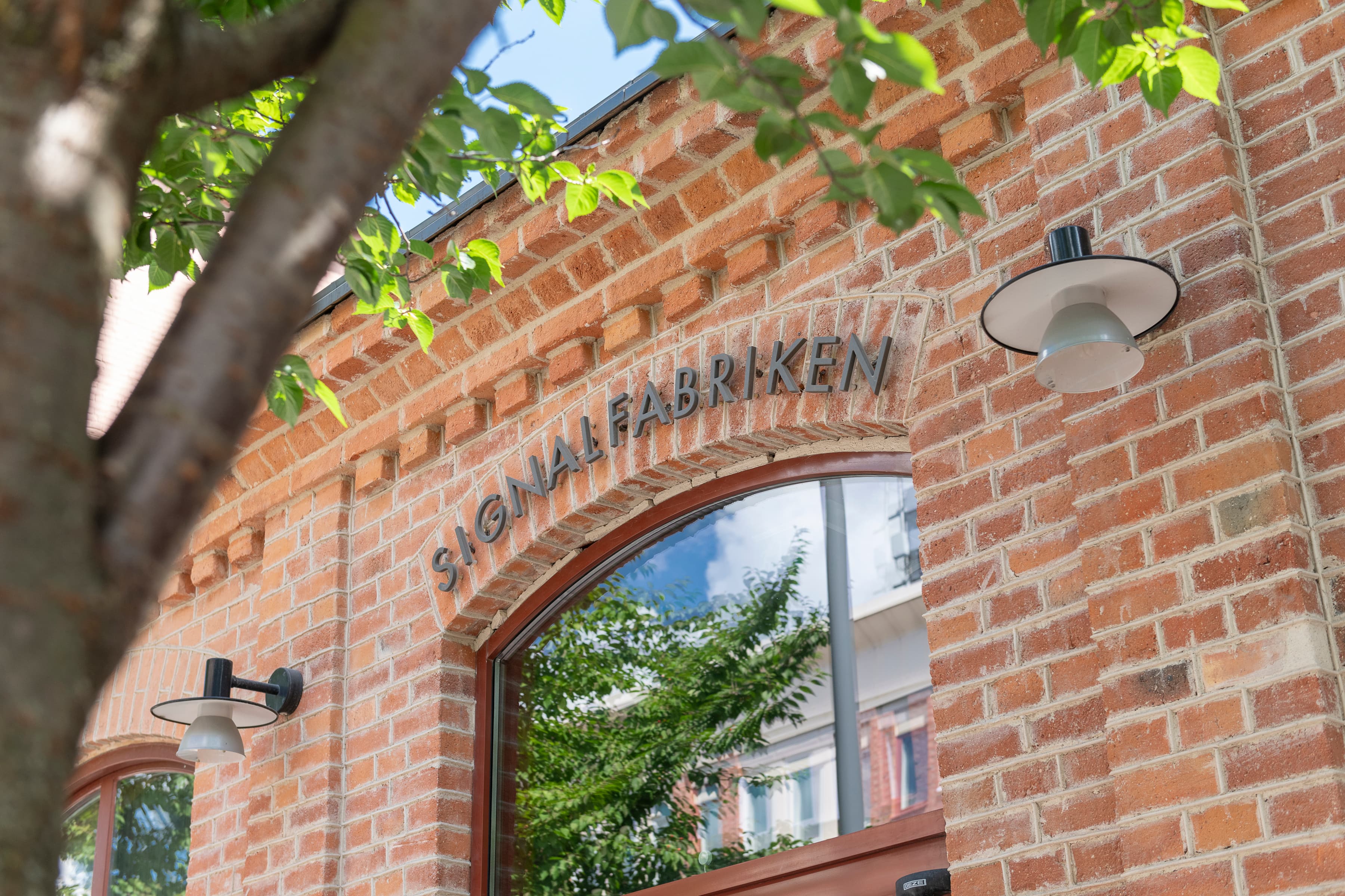 En tegelbyggnad med ett träd framför.