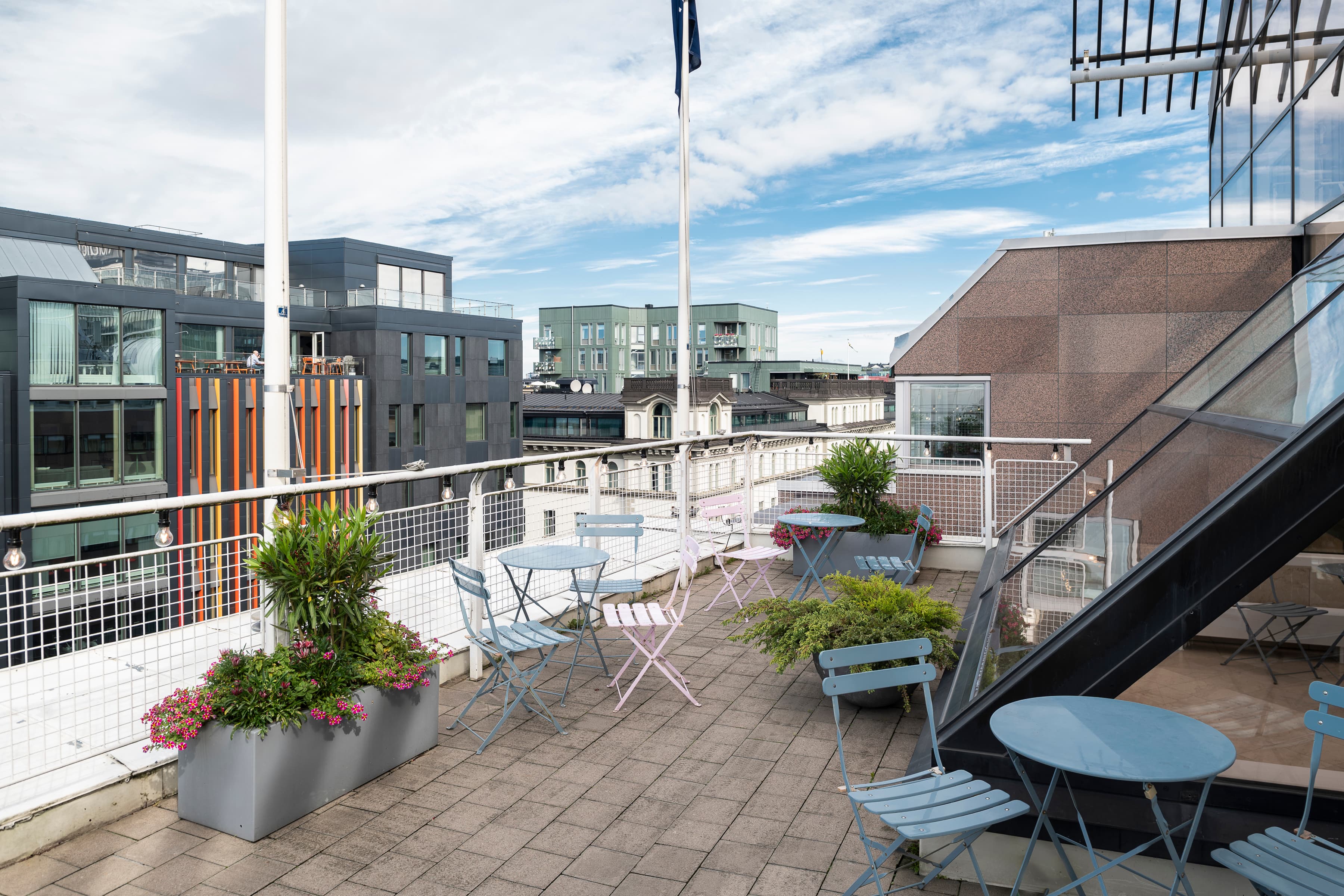 En balkong med bord och stolar och en flagga på en stång.