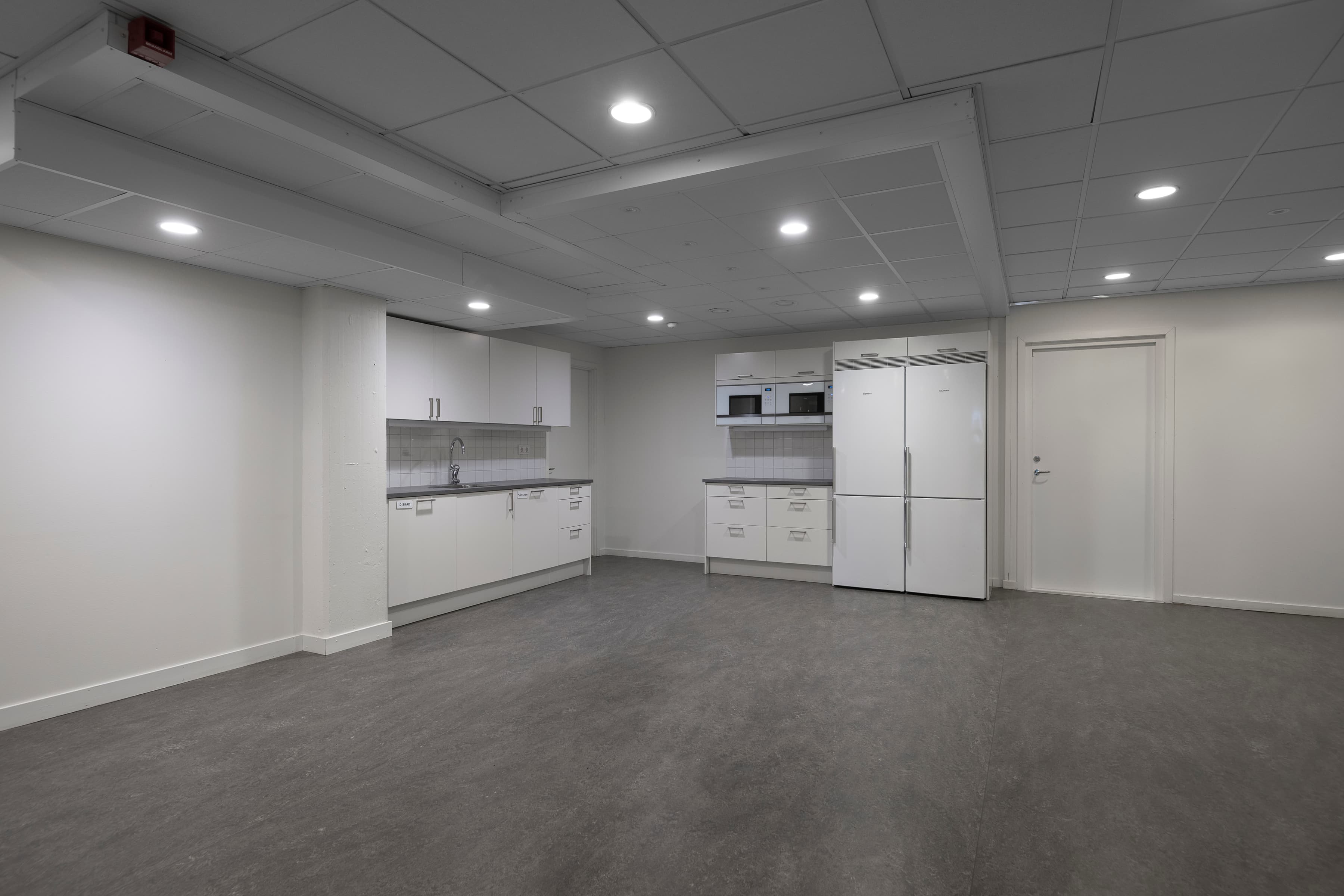 Ett tomt rum med vita skåp och vitvaror.