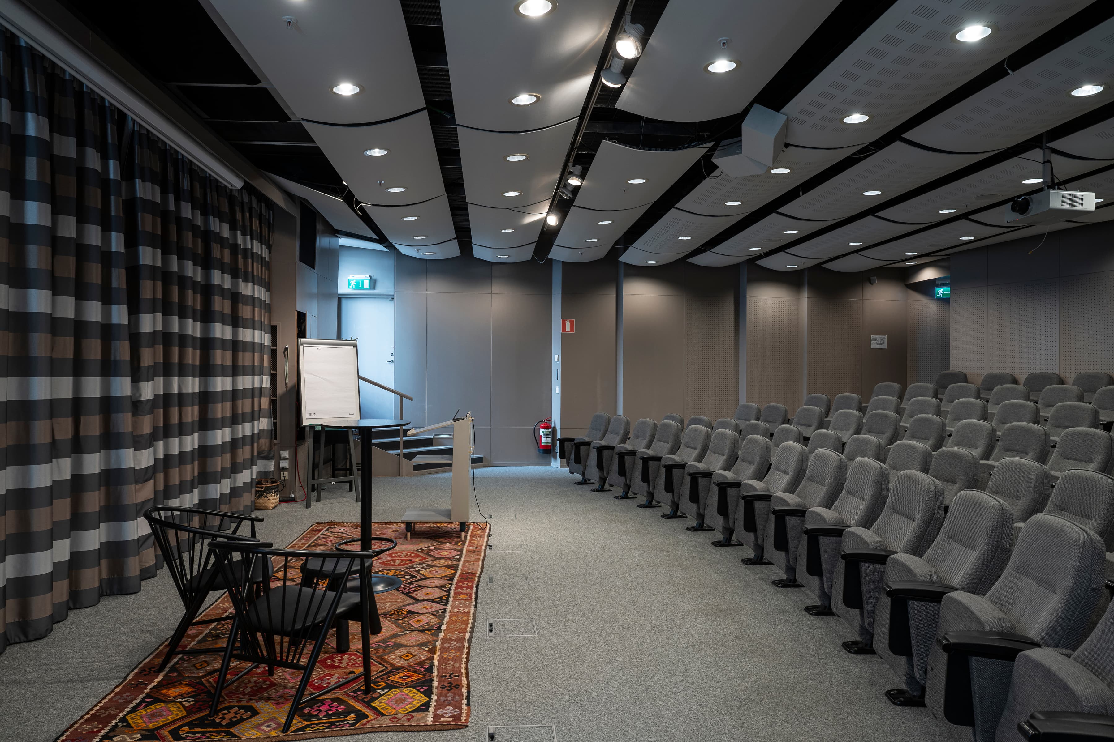 Ett rum med en matta, stolar och en projektorduk.