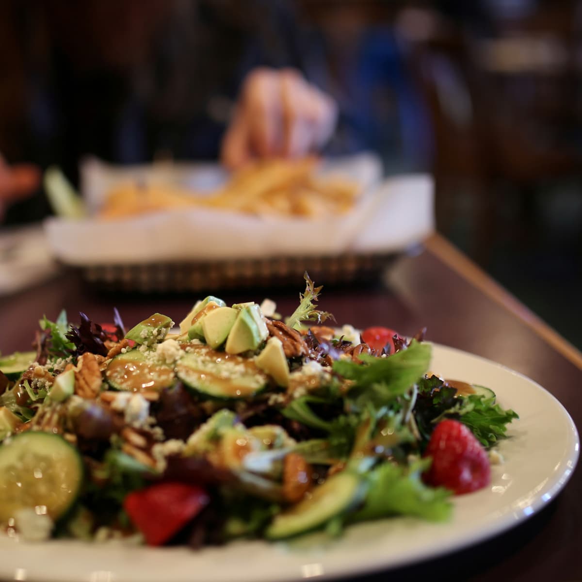 En tallrik med sallad och pommes frites på ett bord.