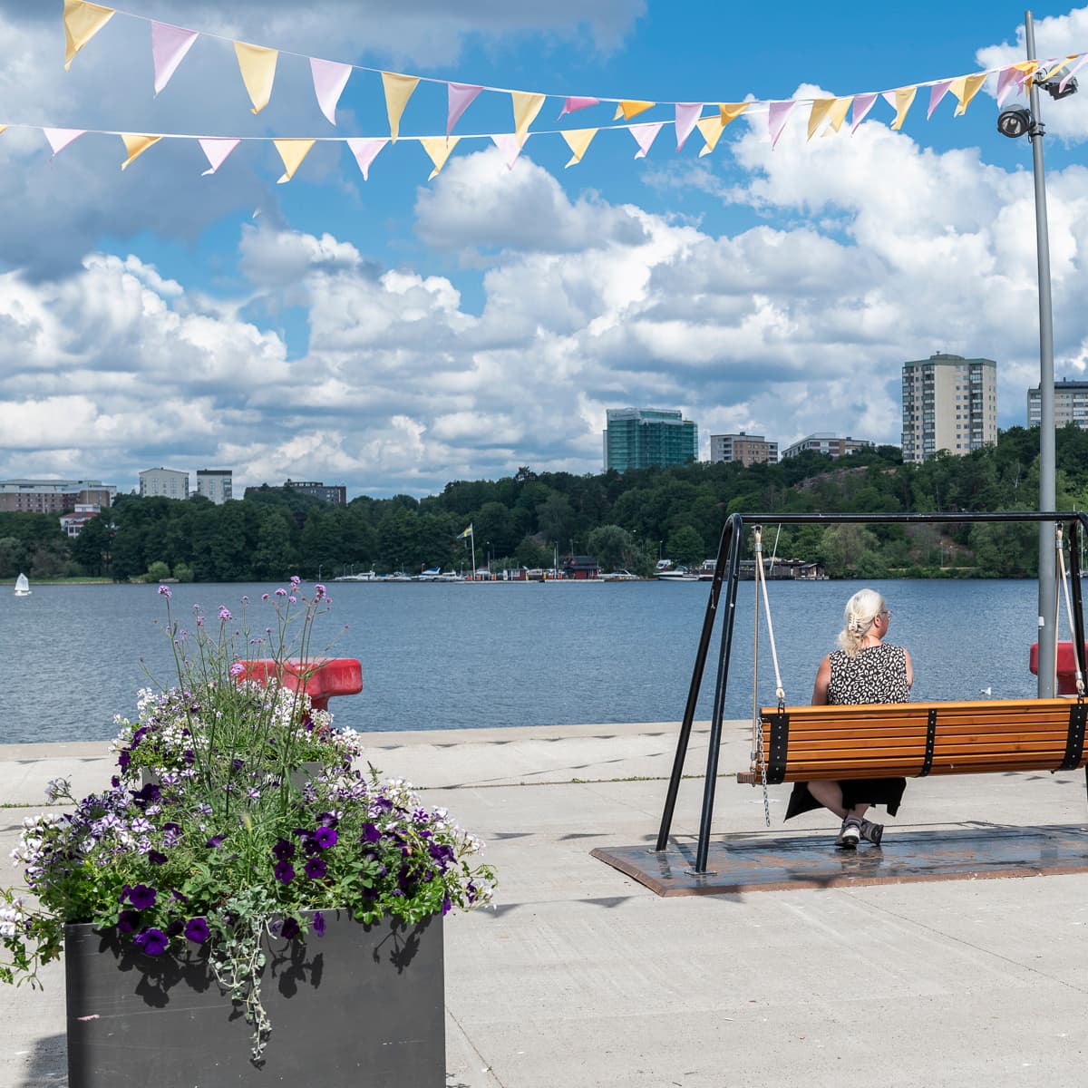 En person som sitter på en bänk nära ett vattendrag.