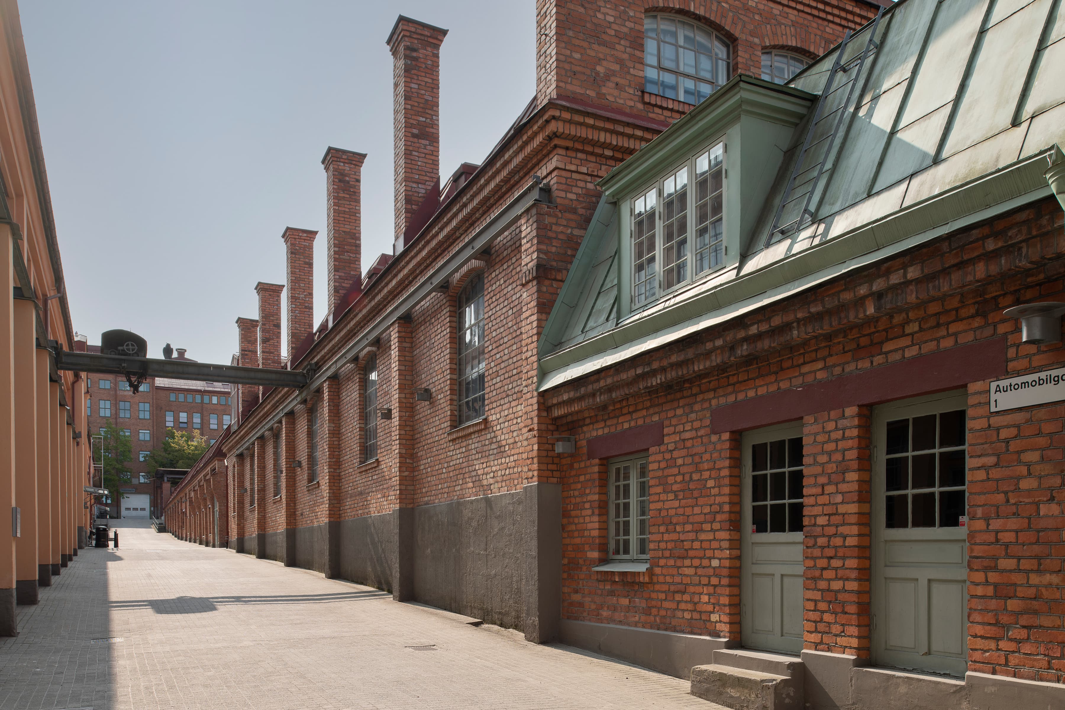 En tegelbyggnad med ett grönt tak intill en trottoar.