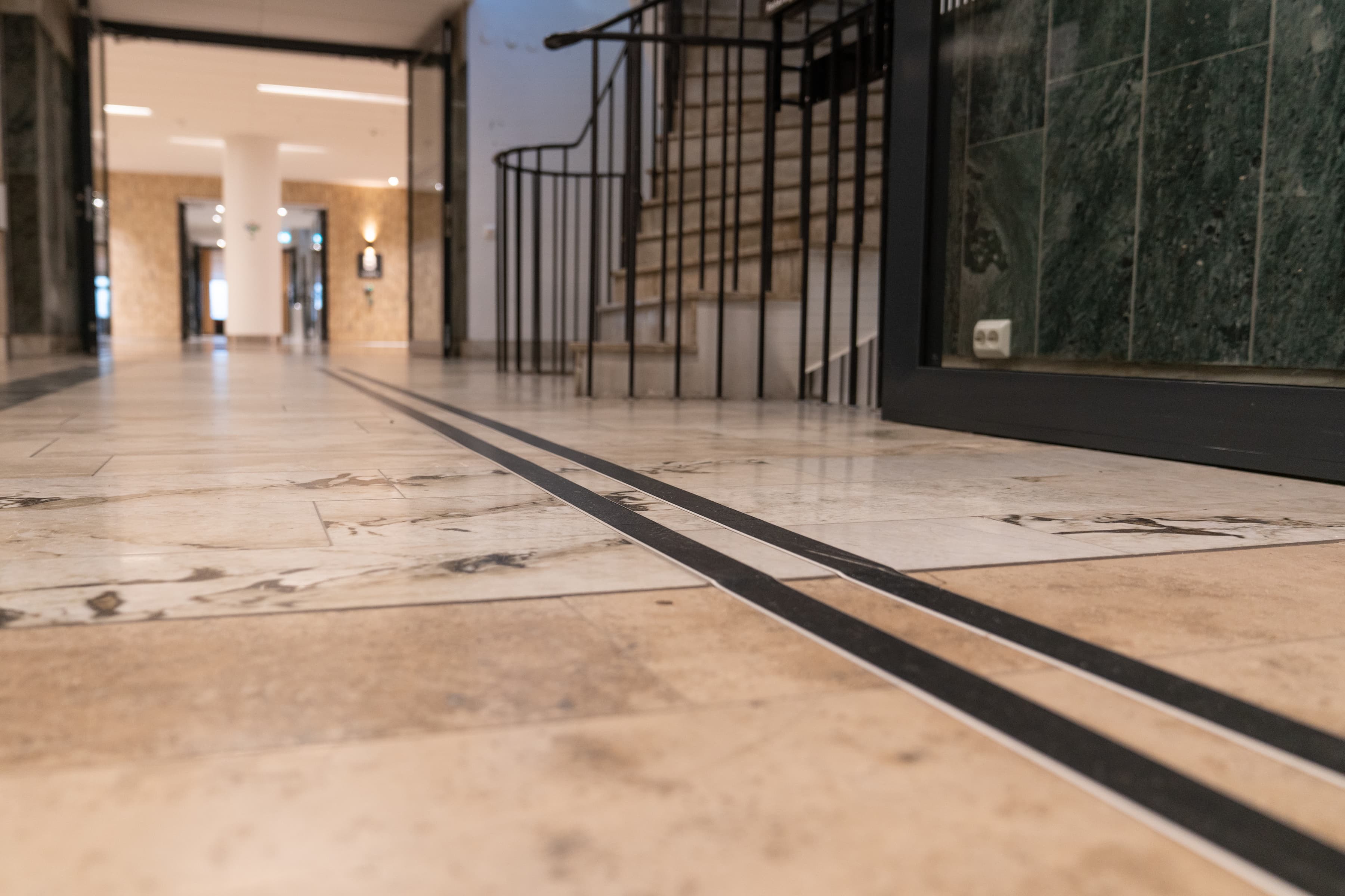 En hall med marmorgolv och en svart dörr.