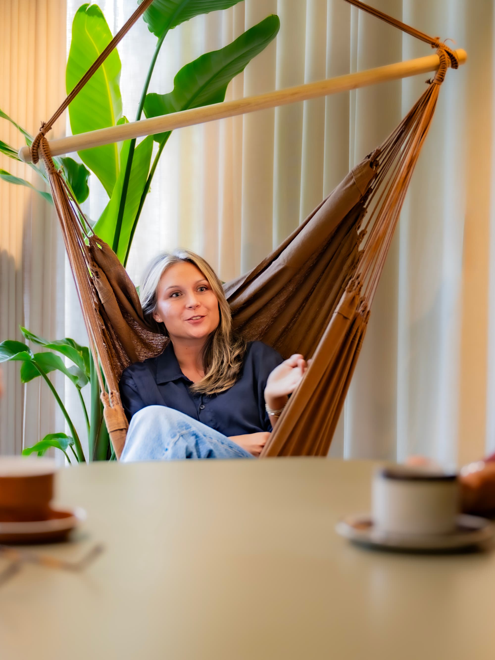 En kvinna som sitter i en hängmatta med en kopp kaffe.