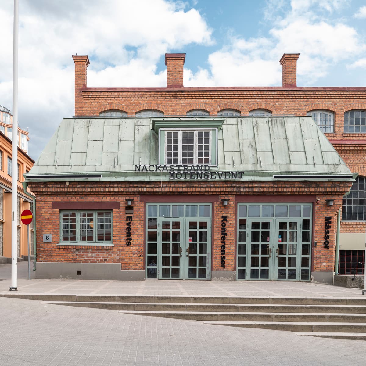 En tegelbyggnad med en flaggstång framför.