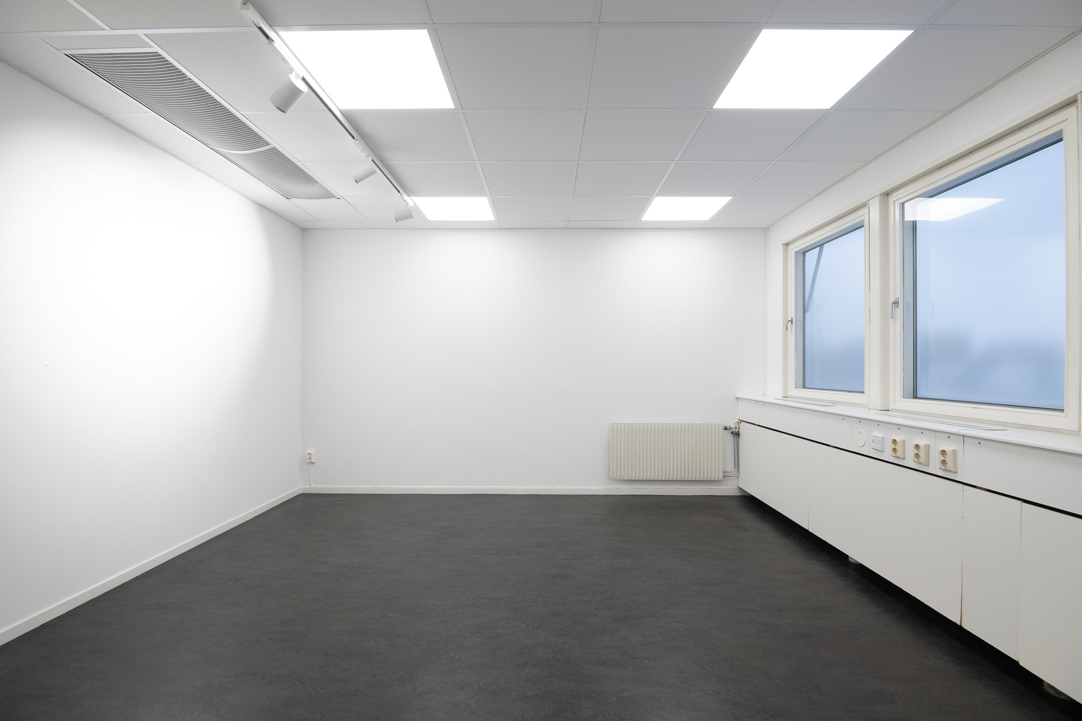 Ett tomt rum med radiator och fönster.