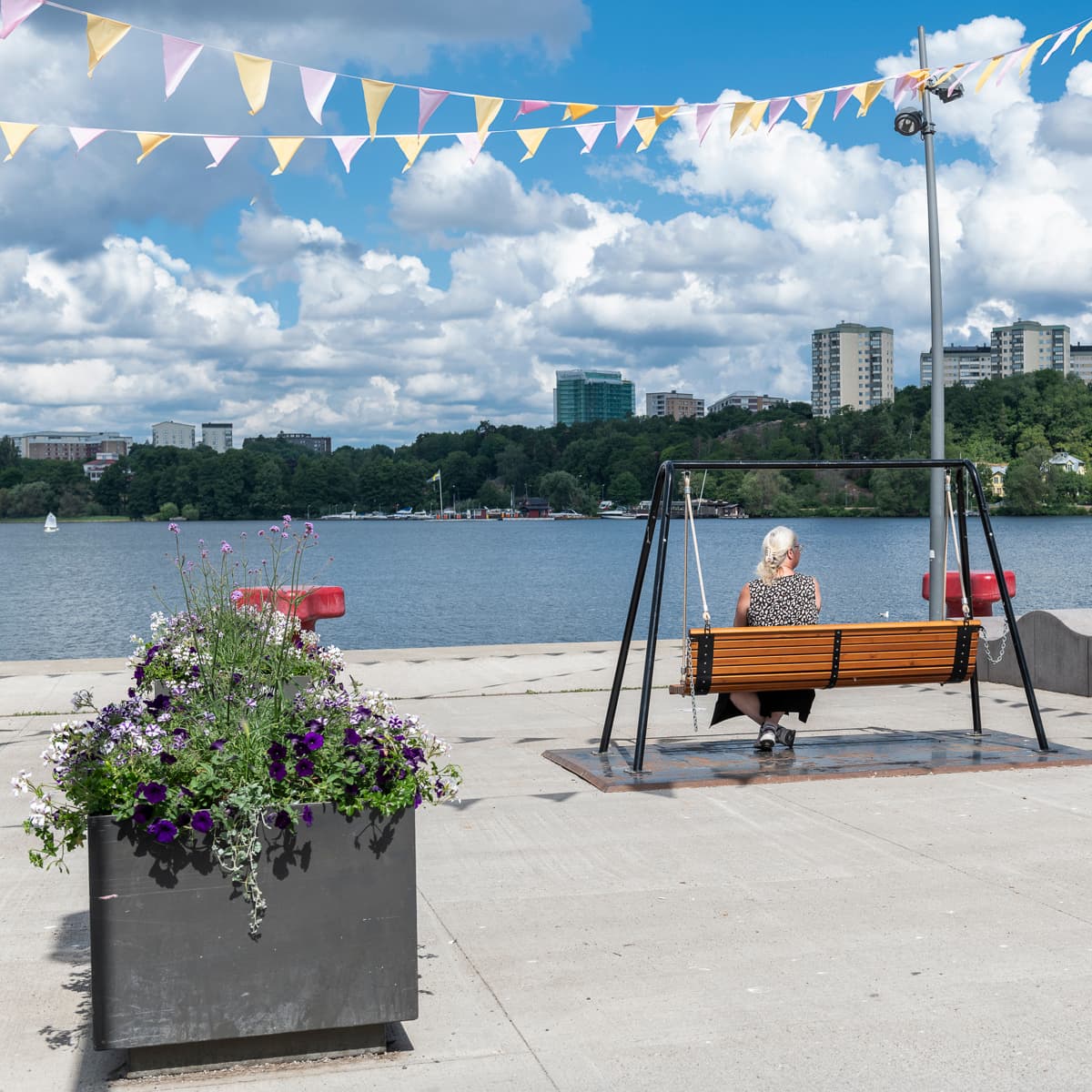 En person som sitter på en bänk nära ett vattendrag.