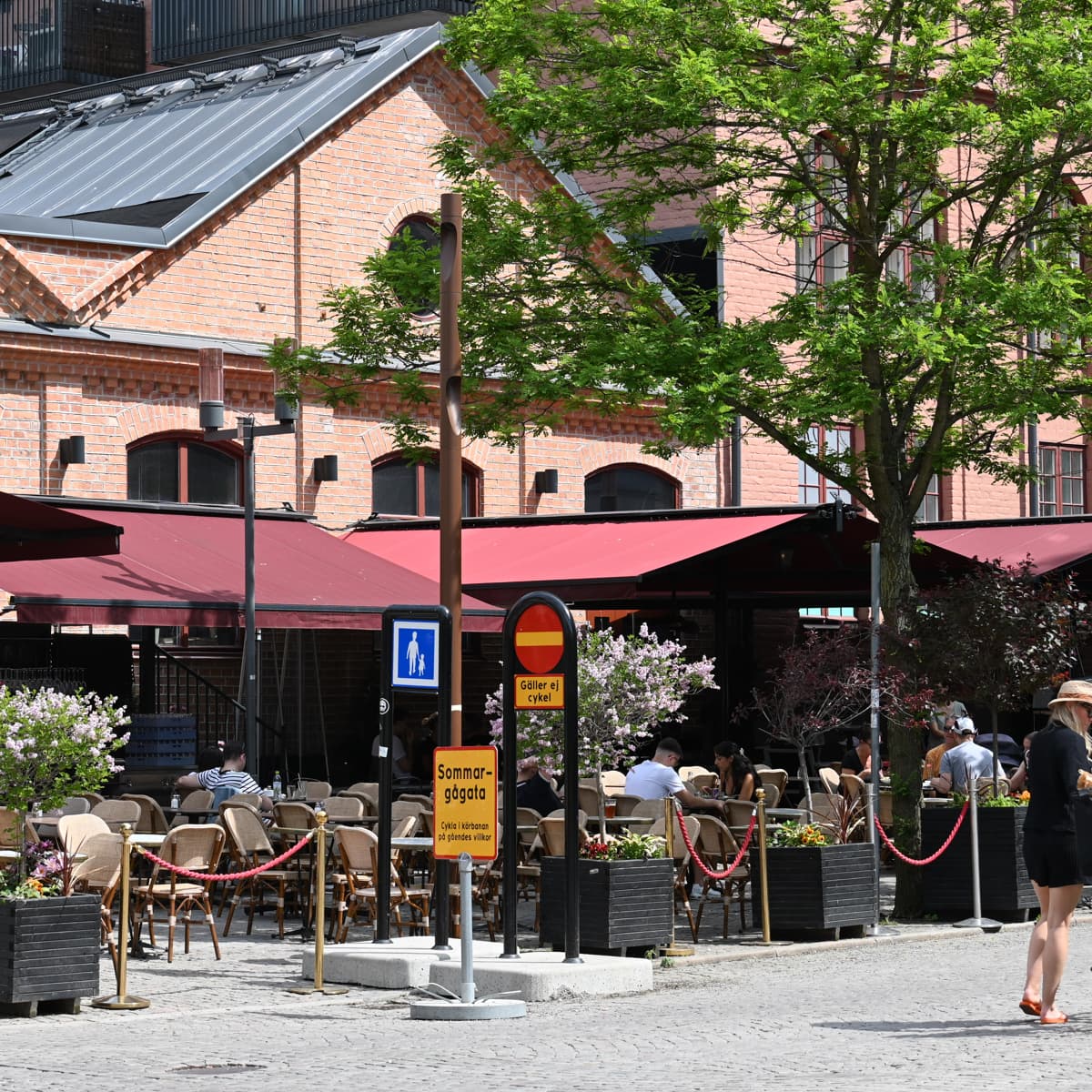 En kvinna går längs en gata bredvid en hög byggnad.
