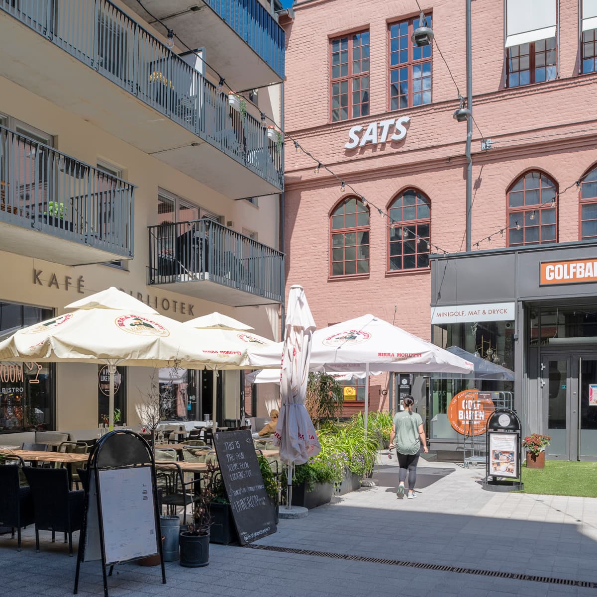 En grupp bord och parasoller framför en byggnad.