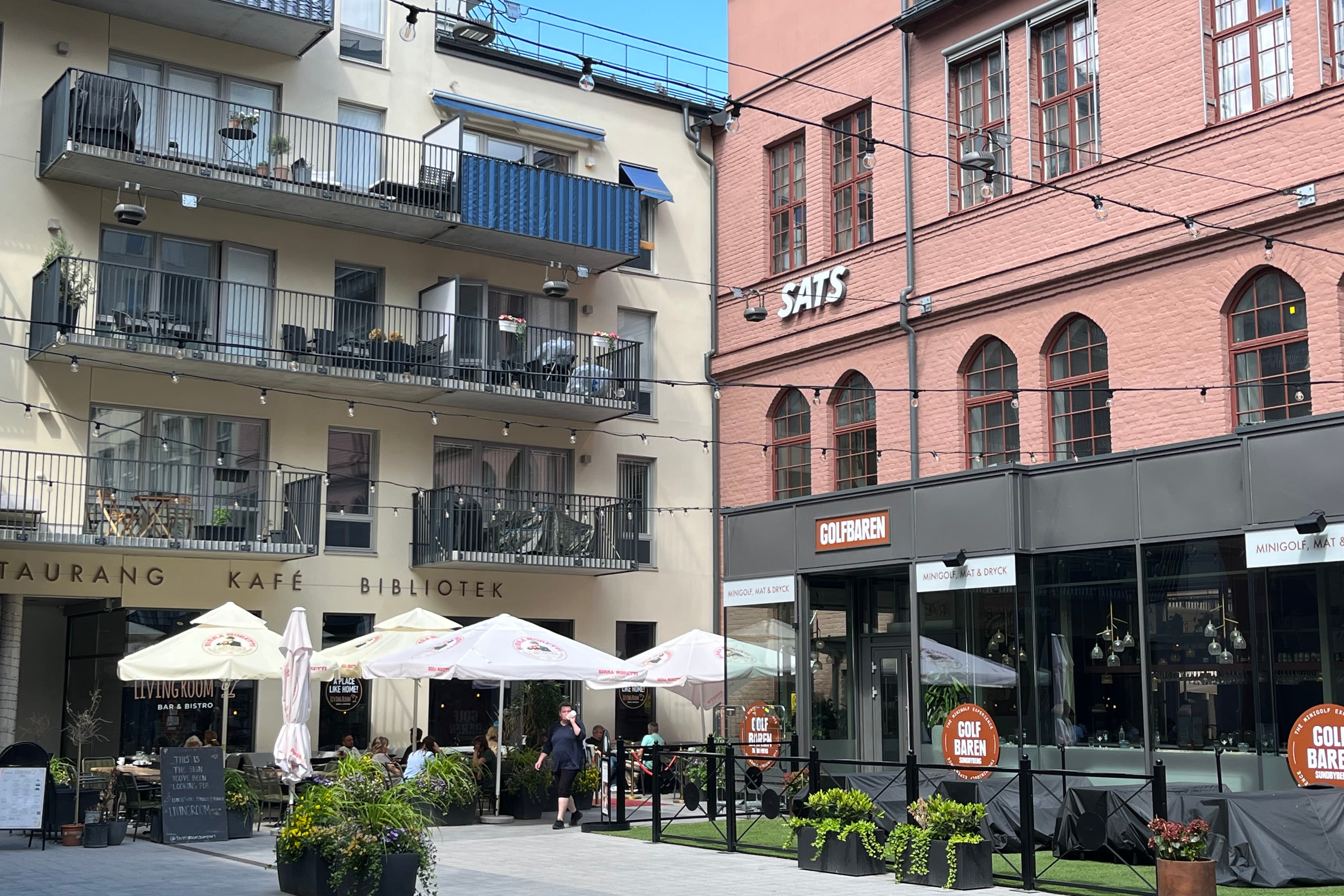 En grupp människor som går längs en gata bredvid höga byggnader.