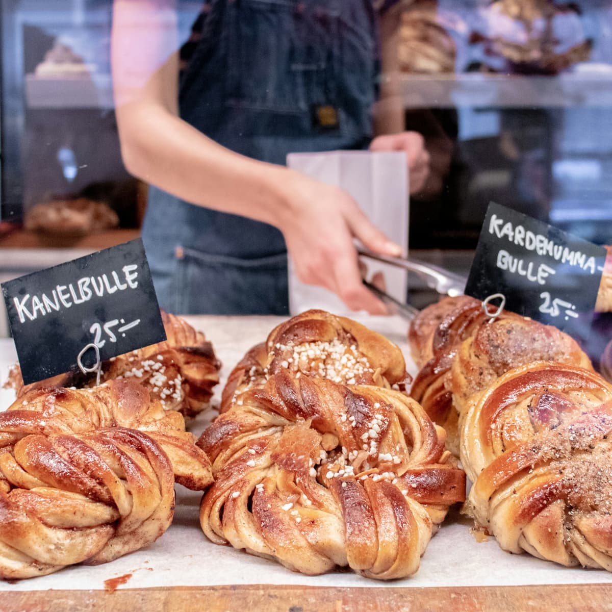 En person som står bakom en utställning av bakverk.