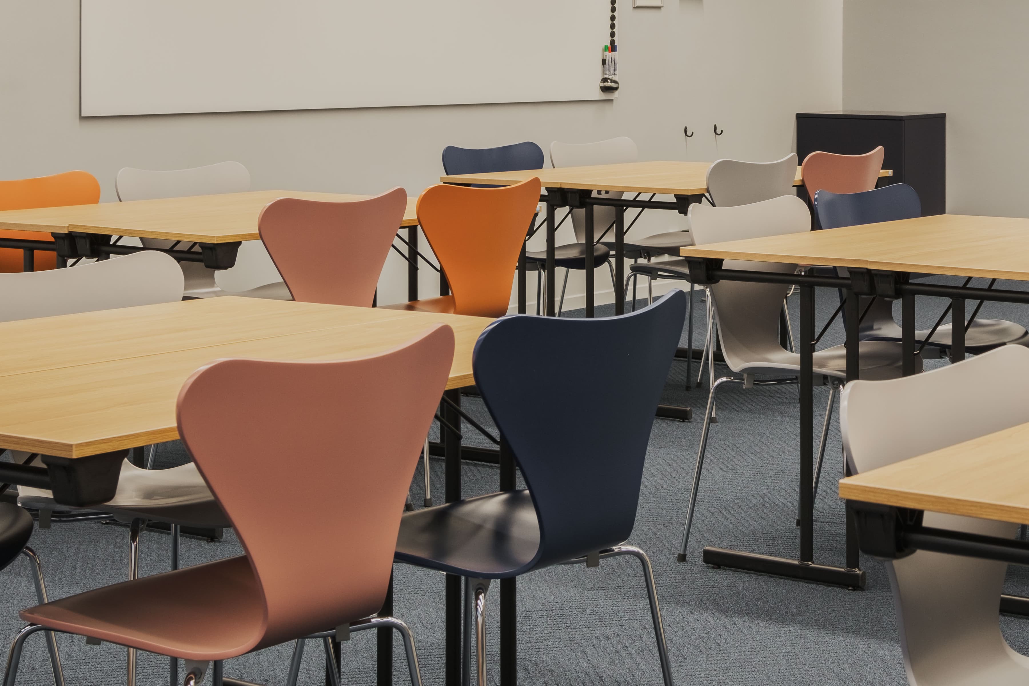 Ett klassrum med bord och stolar och en projektorduk.