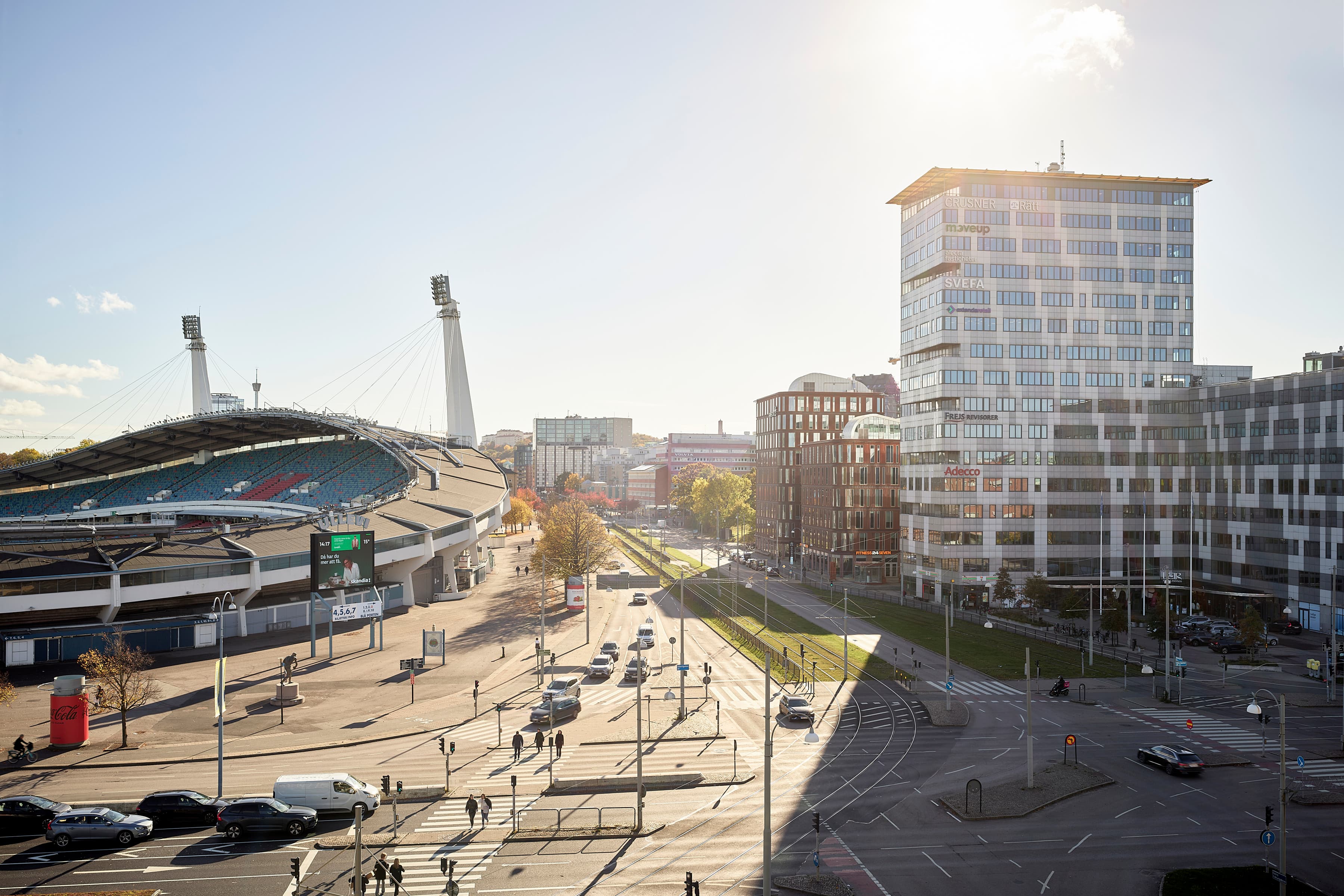 Solen skiner över en gata i en stad.