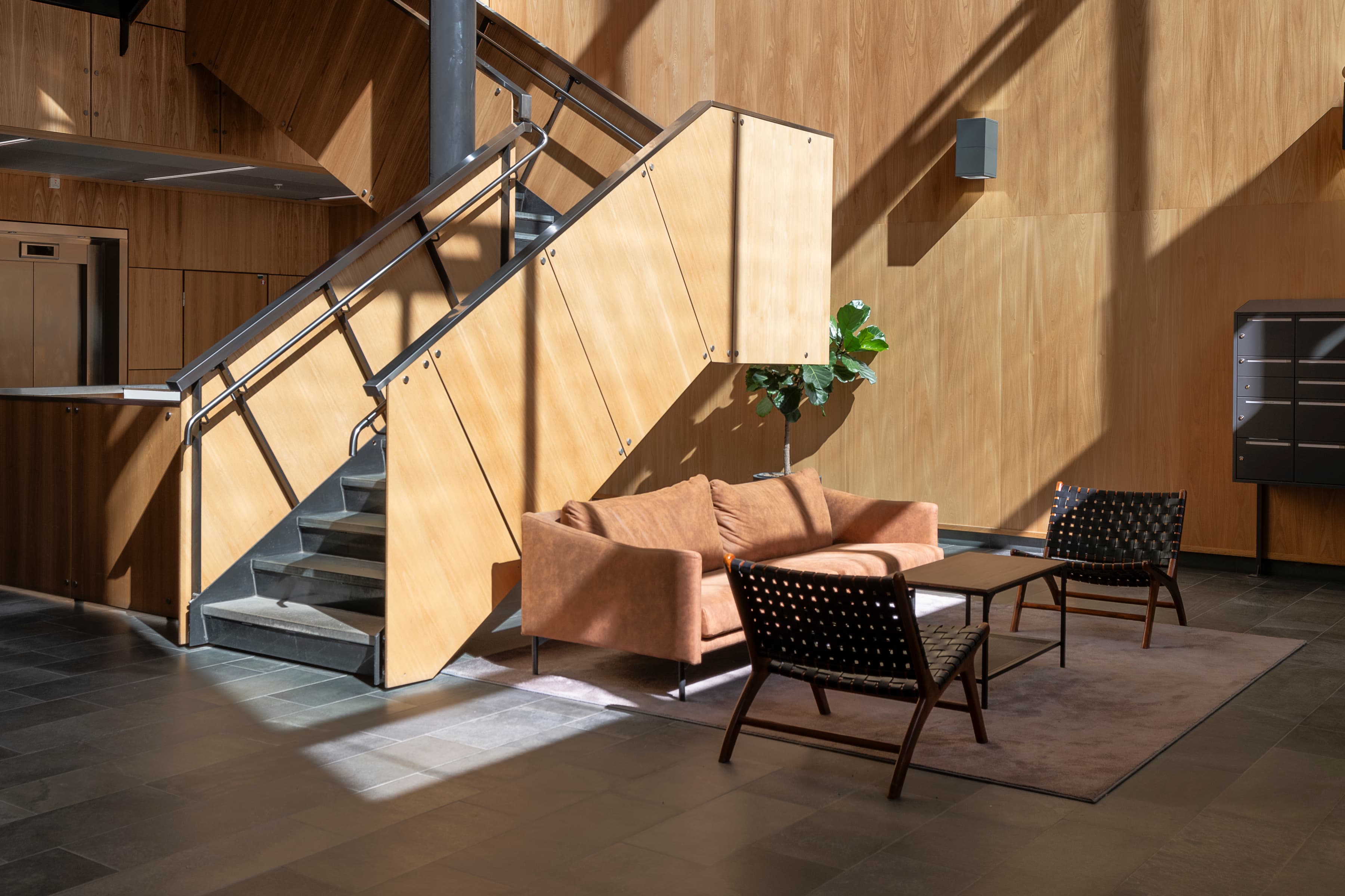 Ett vardagsrum med en soffa en stol och en trappa.