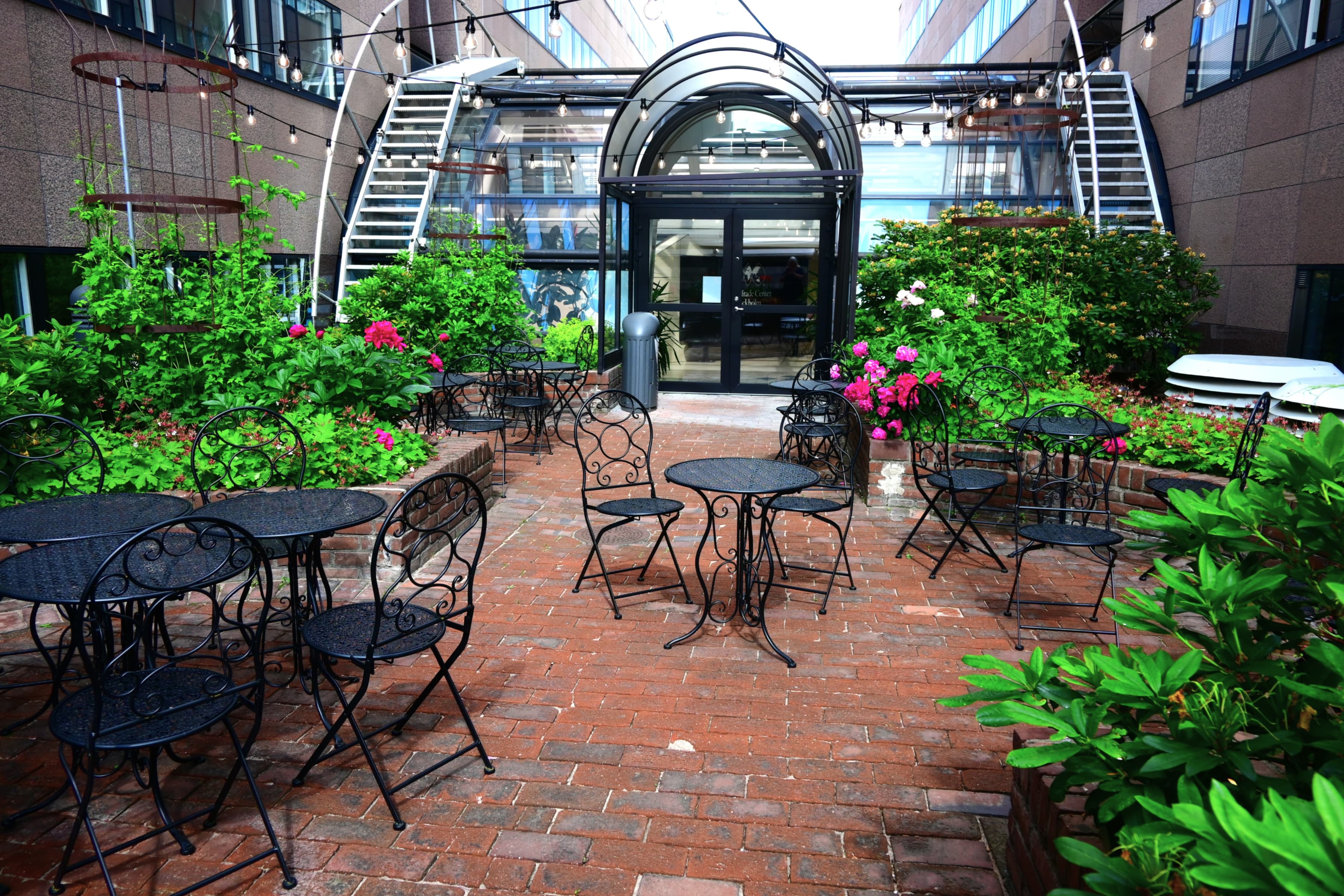 En innergård med bord och stolar och en spiraltrappa.