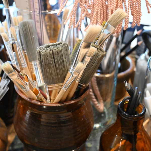 En brun vas fylld med massor av olika typer av borstar.