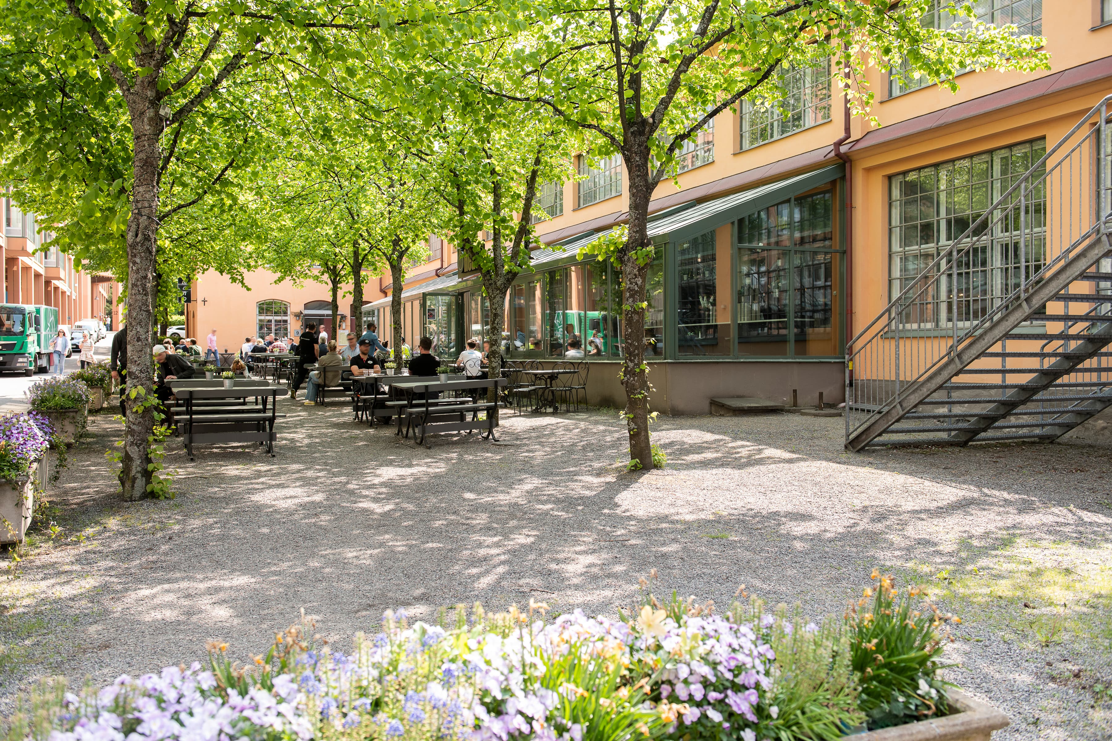 En grupp människor som sitter vid bord i en park.