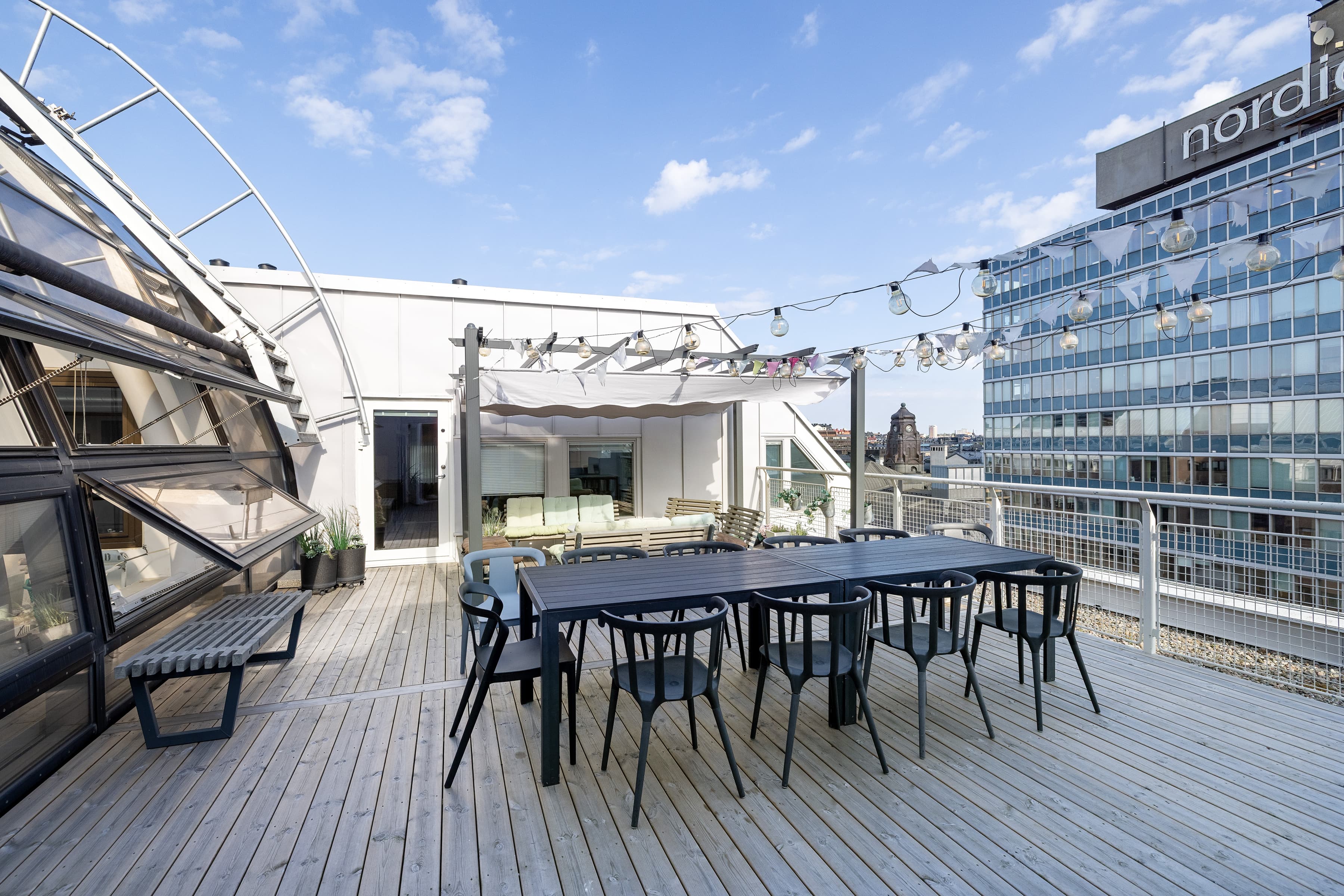 Ett bord och stolar på ett däck med en byggnad i bakgrunden.