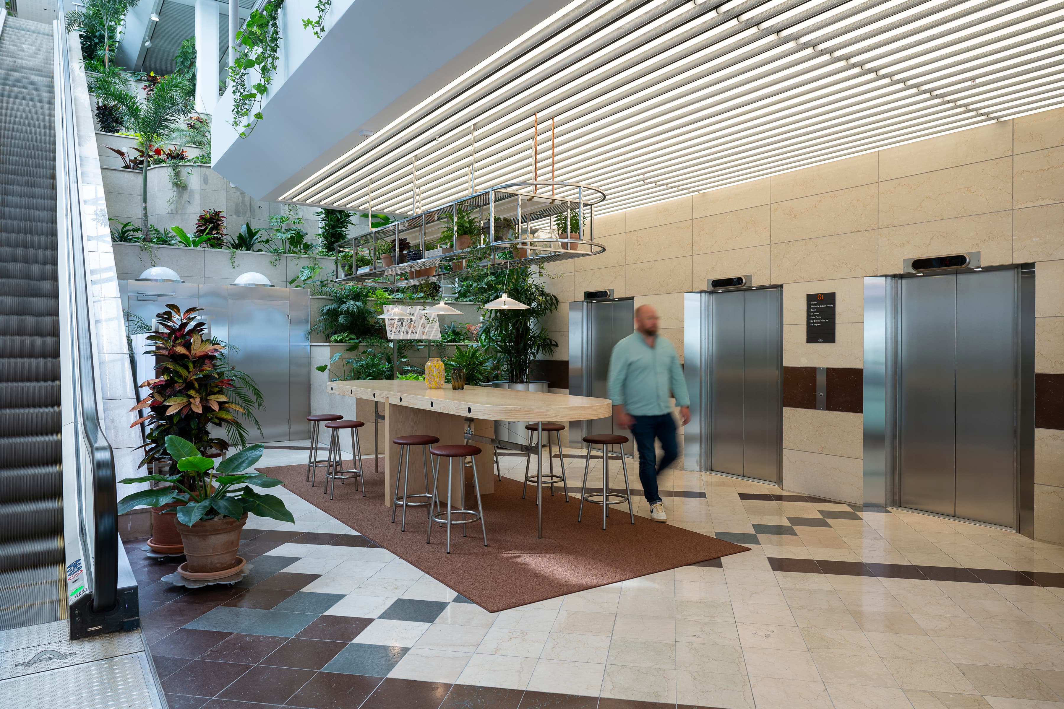 En man går genom en lobby bredvid ett gäng växter.