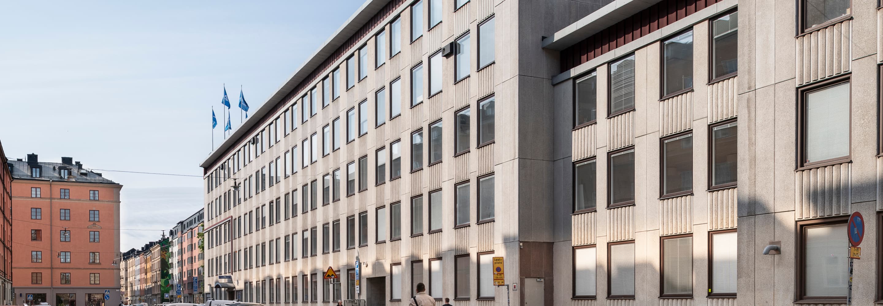 En man åker skateboard på en gata bredvid höga byggnader.