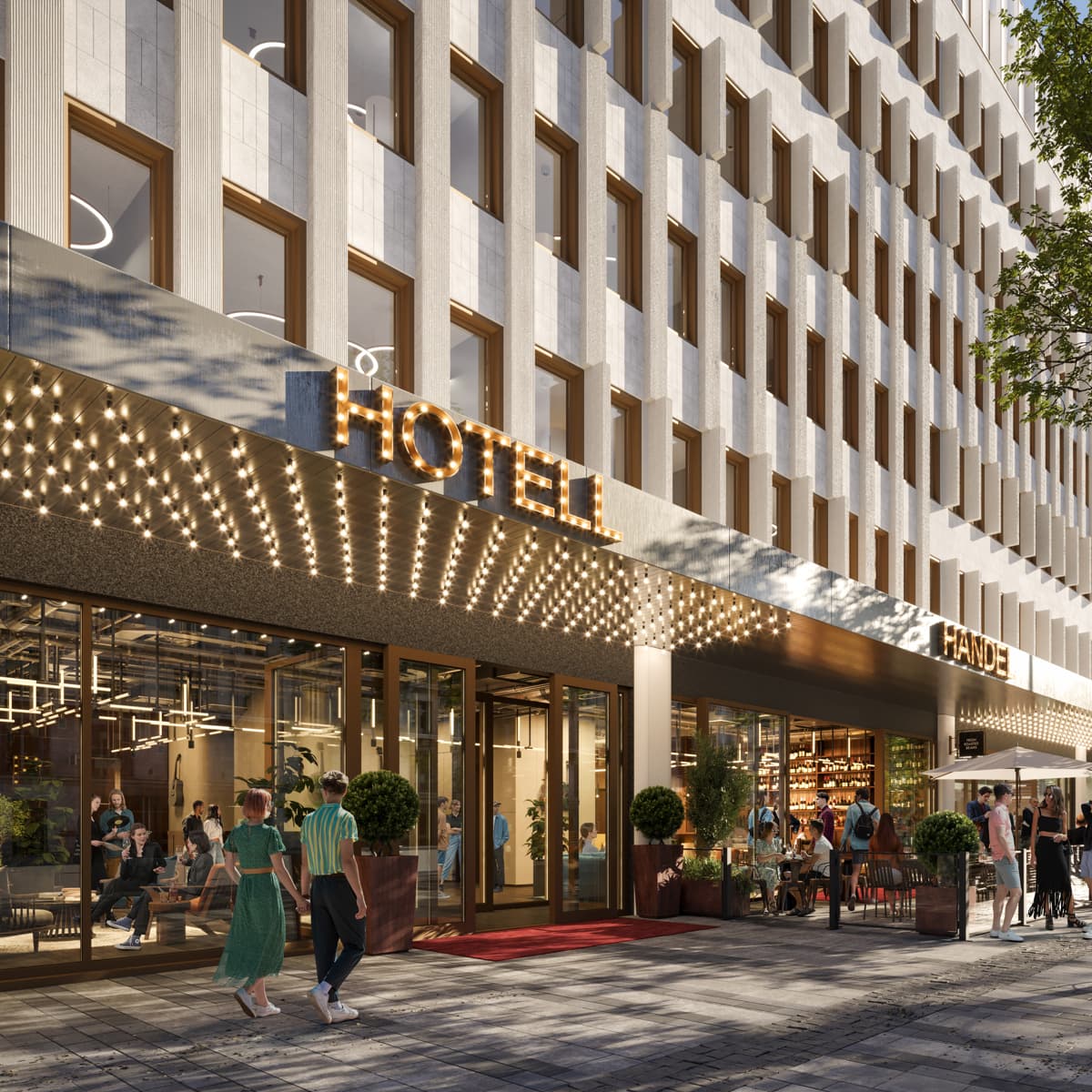 En grupp människor som går längs en gata bredvid en hög byggnad.