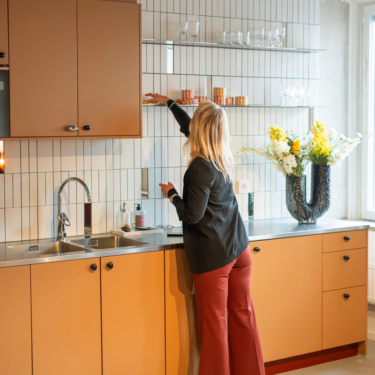 En kvinna står i ett kök bredvid ett handfat.