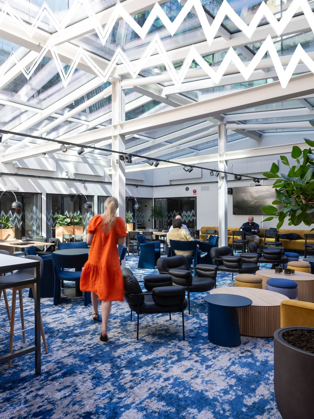 En kvinna i orange klänning går genom ljusgården på Flexiwork Hovet.