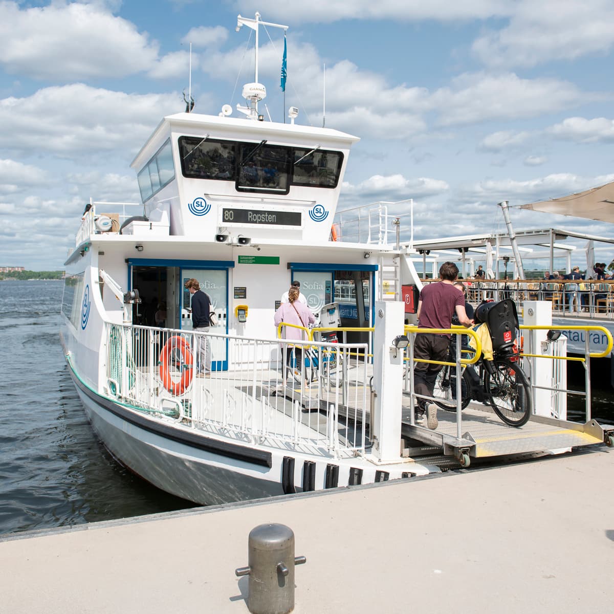 En grupp människor som står på en brygga bredvid en båt.