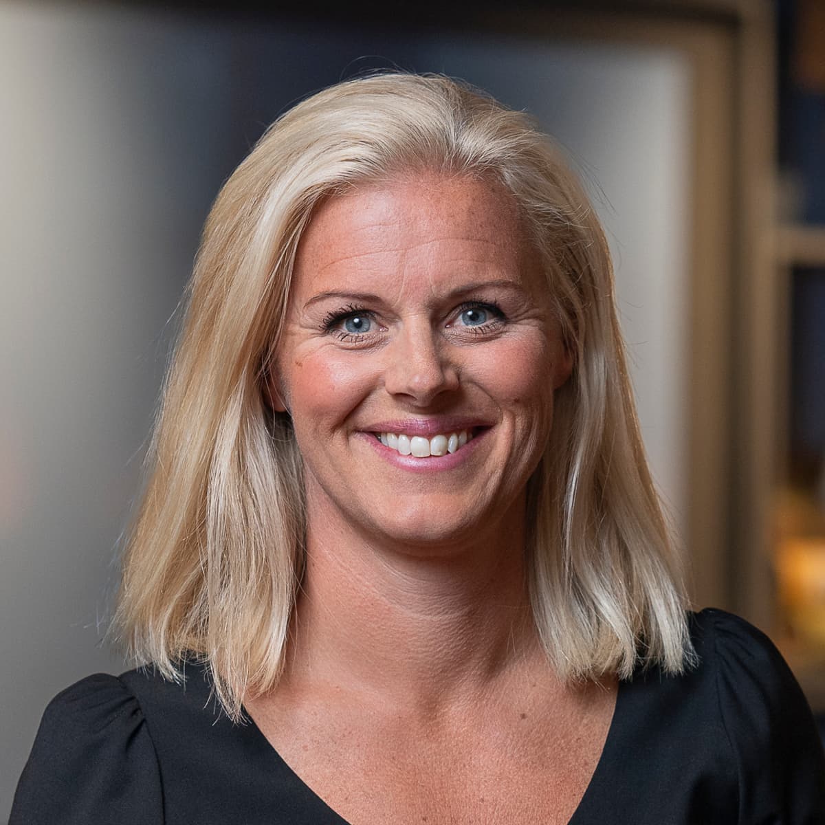 En kvinna i svart klänning står i ett rum.