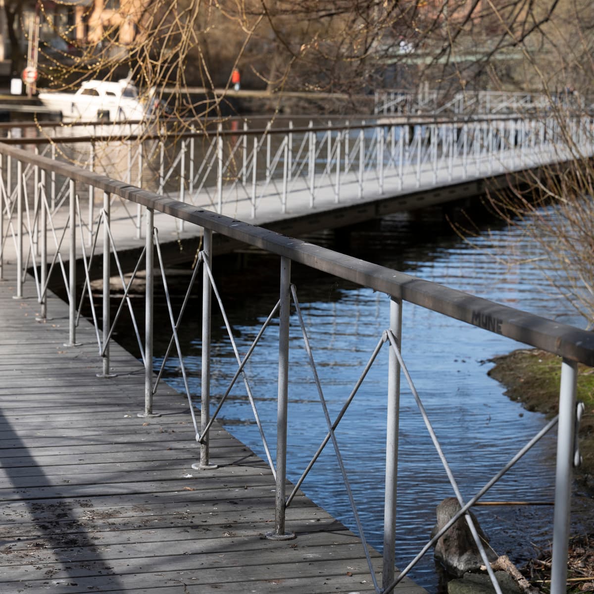 En bro över ett vattendrag med en båt i bakgrunden.