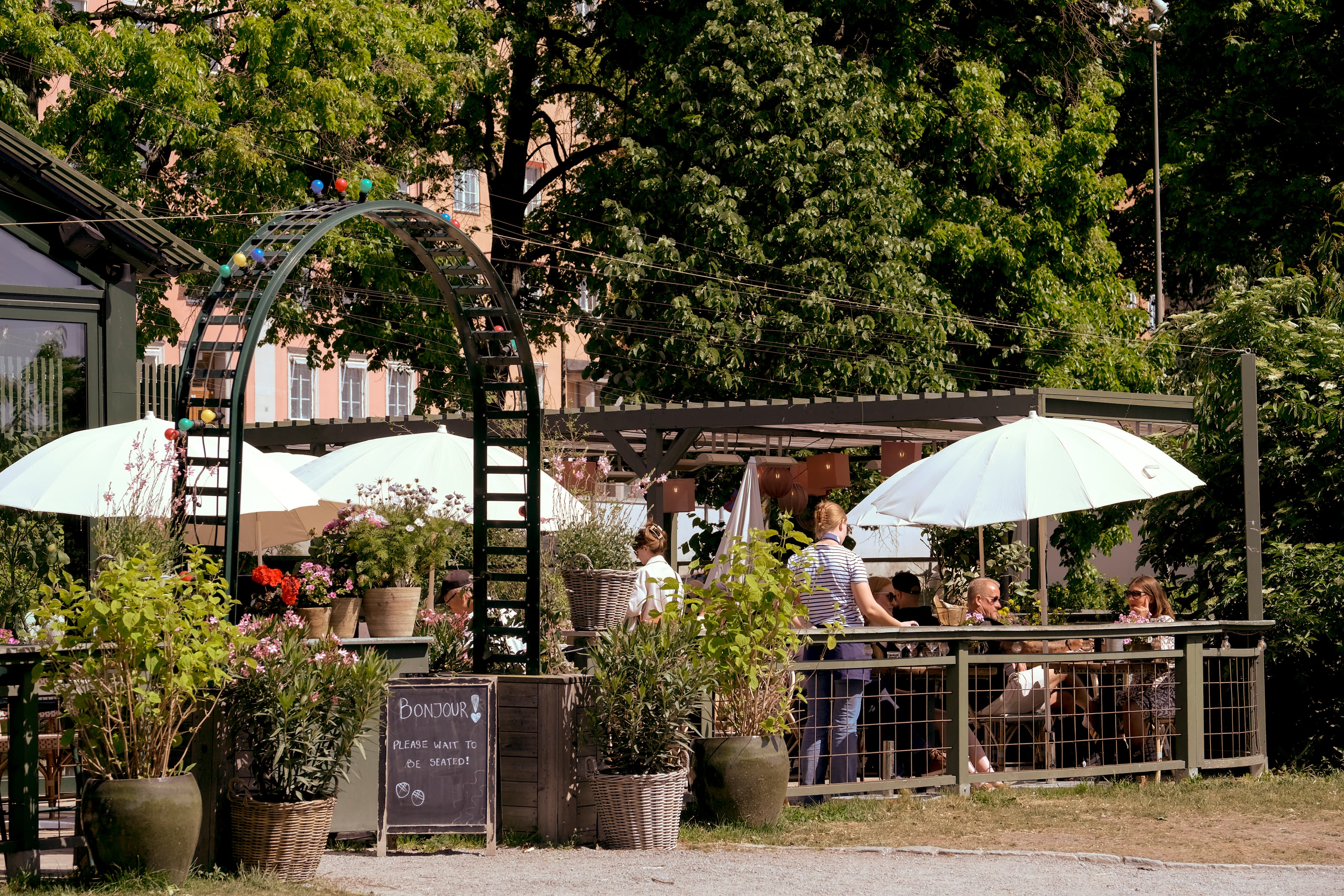 En grupp människor som sitter vid ett bord under paraplyer.
