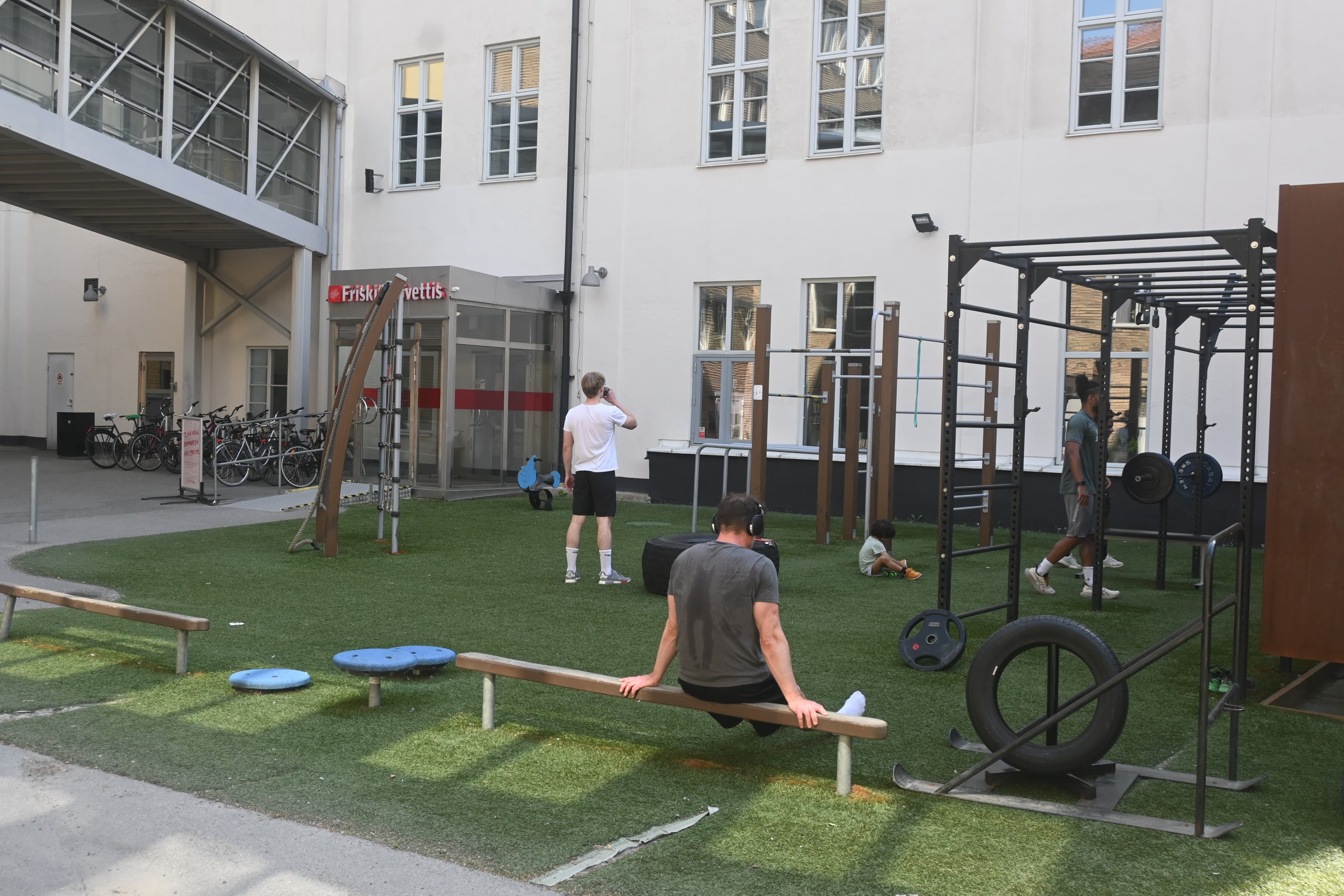 En man sitter på en bänk framför ett gym.