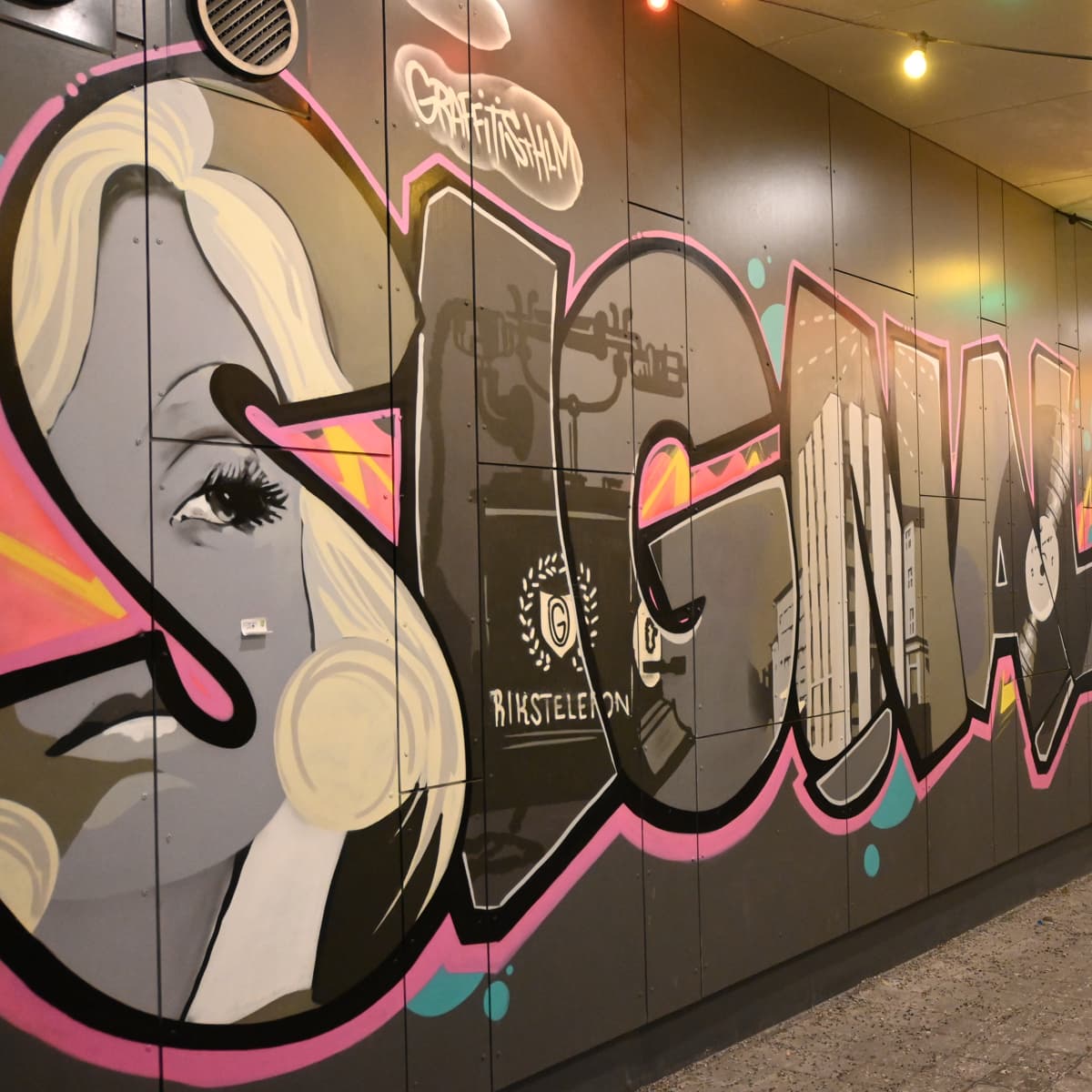 En vägg täckt av massor av graffitti och lampor.