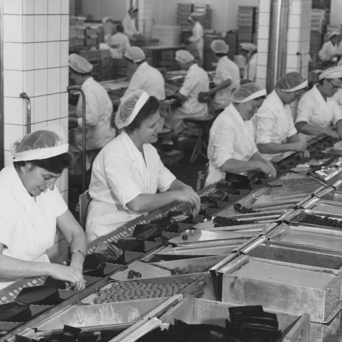Ett svartvitt foto av arbetare i en fabrik.