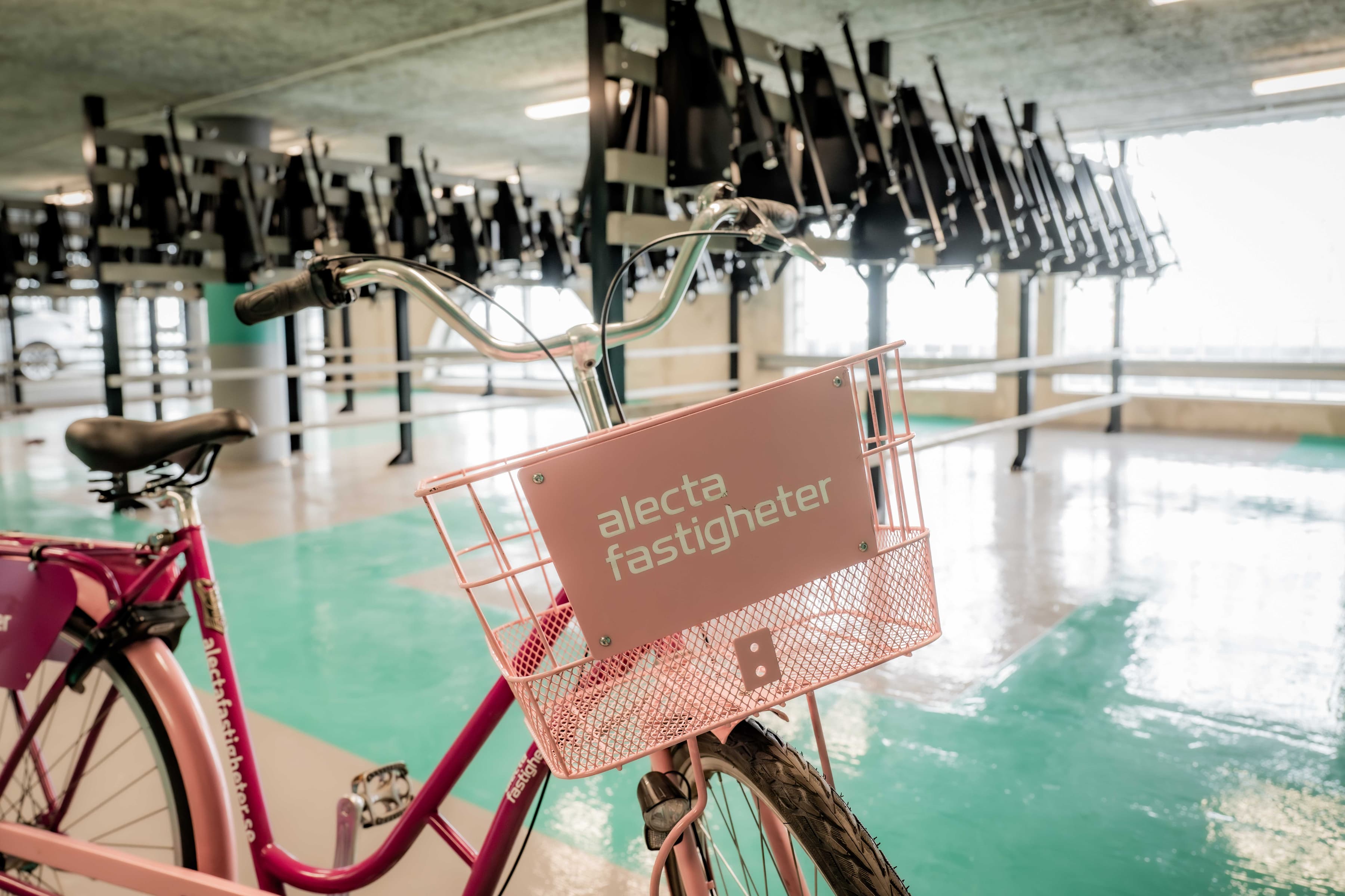 En rosa cykel som står parkerad i ett parkeringshus.