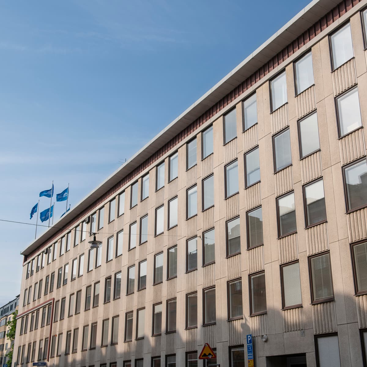 En hög byggnad med många fönster intill en gata.