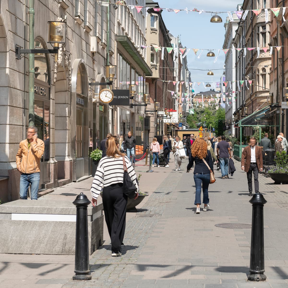 En grupp människor som går längs en gata bredvid höga byggnader.