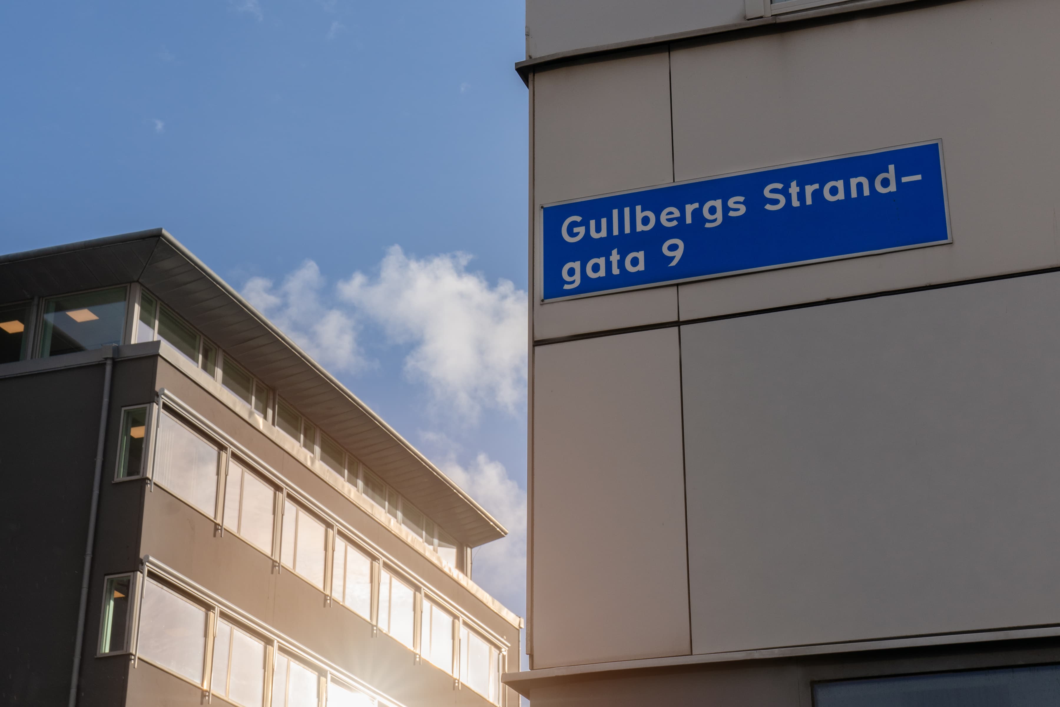 En hög byggnad med en blå gatuskylt på sidan.