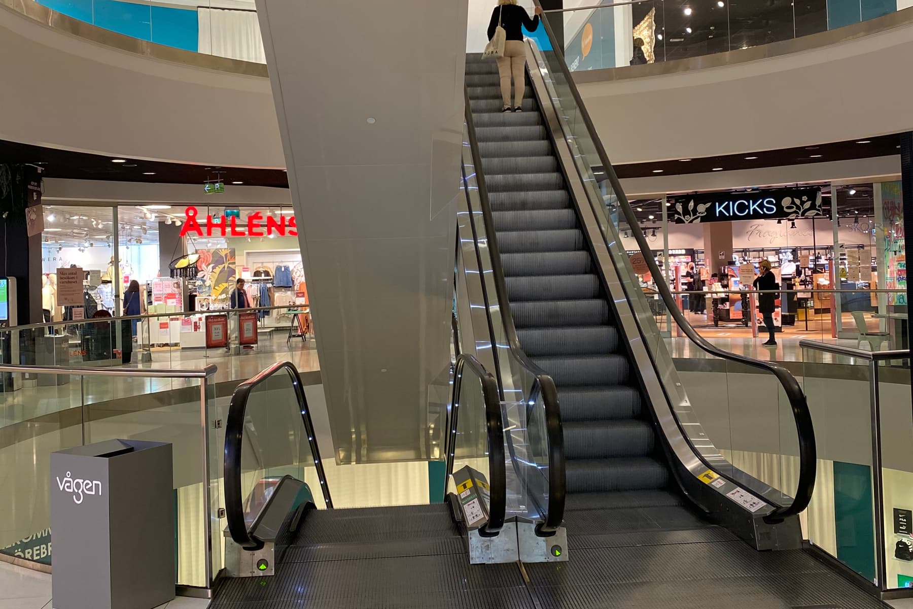 En rulltrappa i ett köpcentrum med en person på rulltrappan.