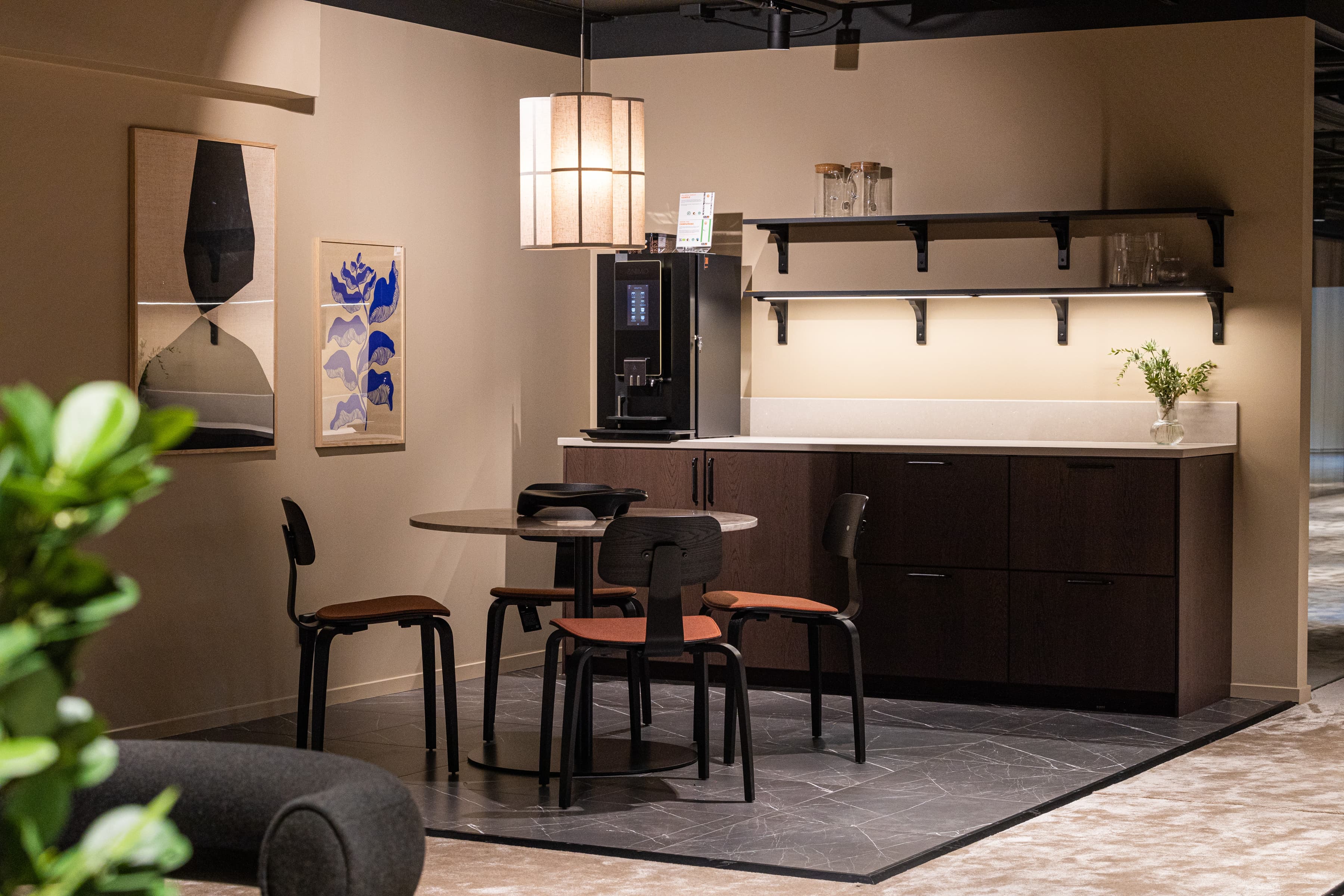 Ett kök med bord, stolar och kylskåp.