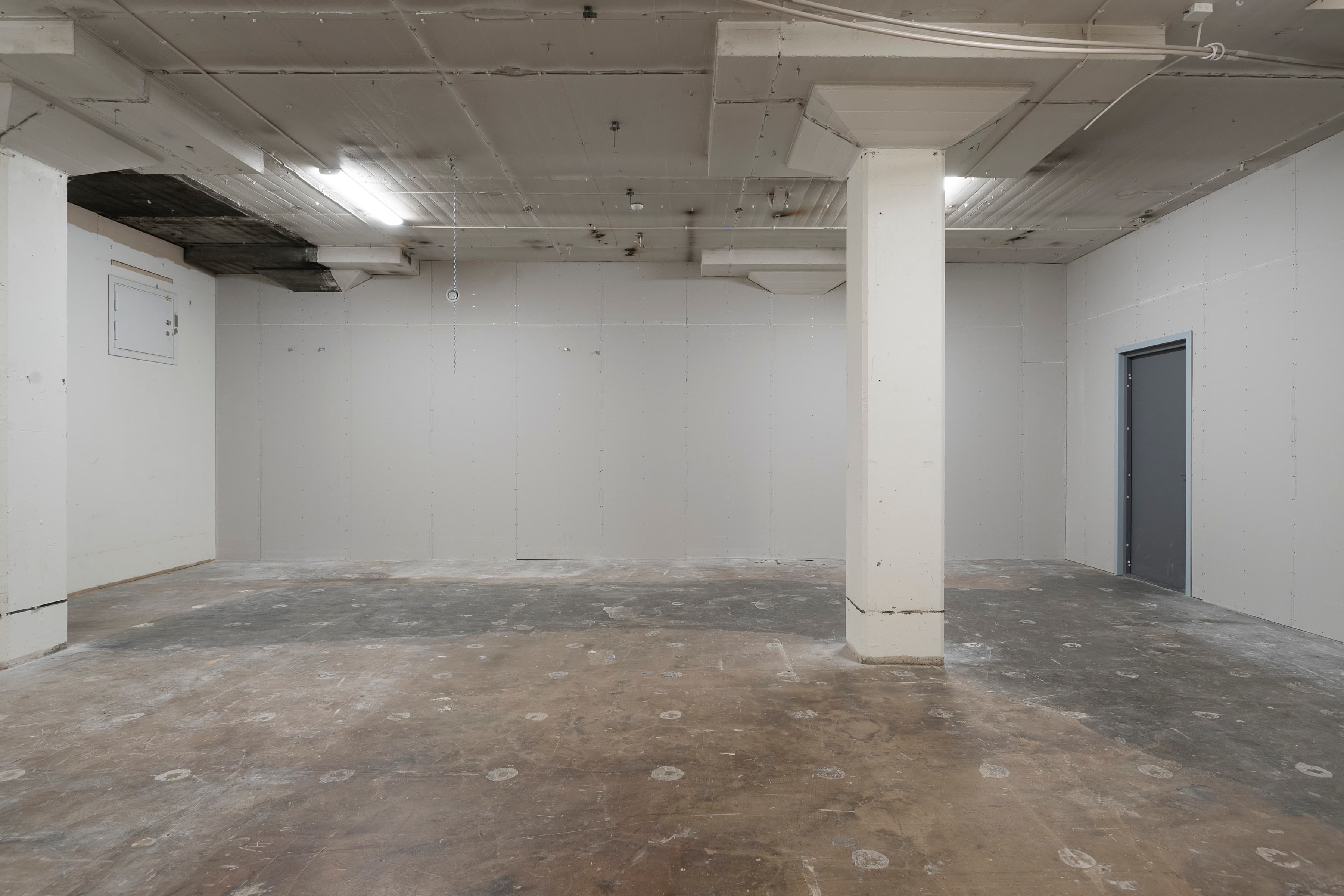 Ett tomt rum med vita väggar och en dörr.