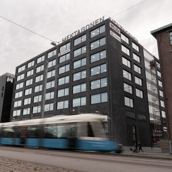 Ett blått och vitt tåg som passerar en hög byggnad.