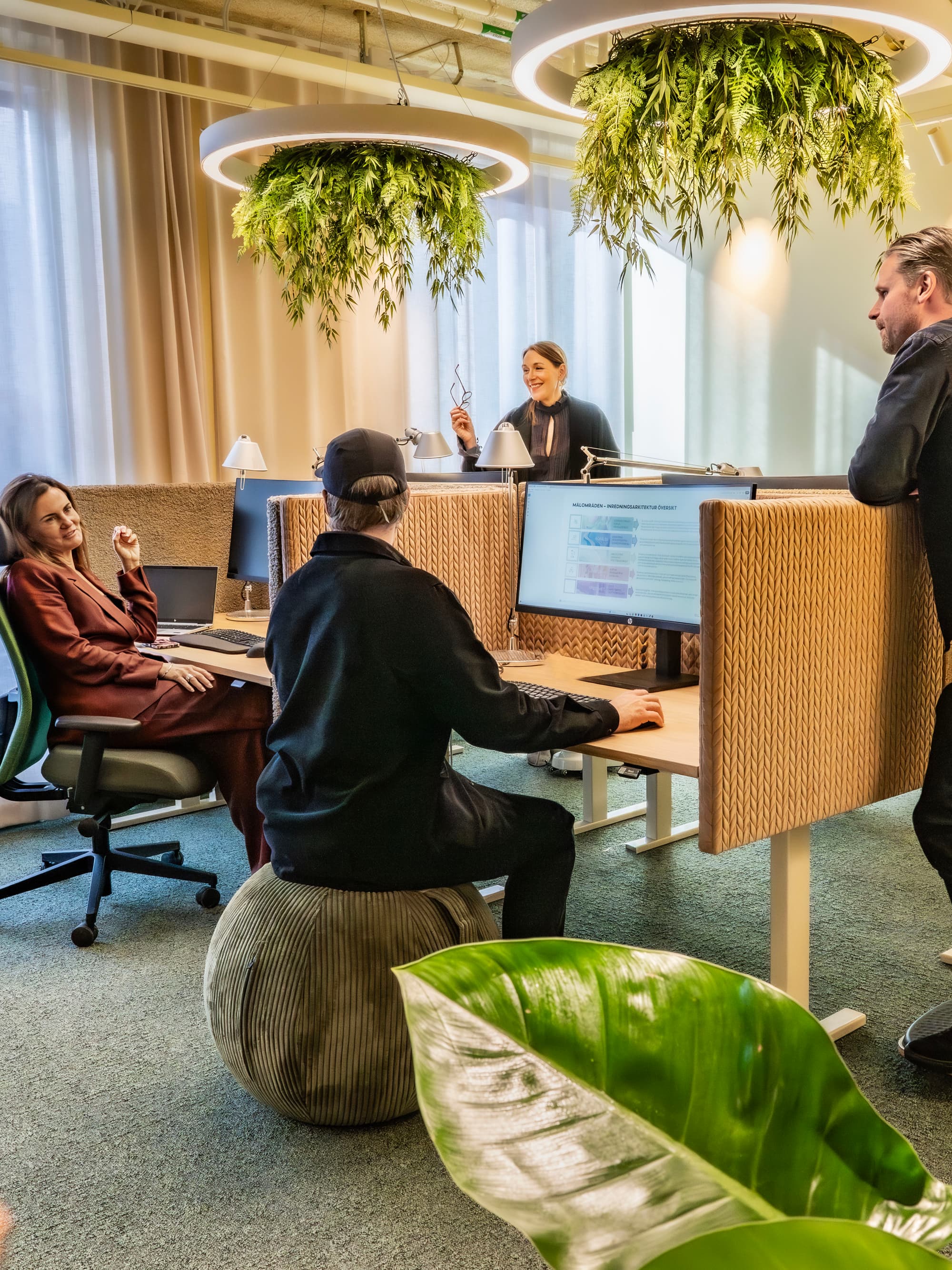 En grupp människor som sitter runt ett skrivbord på ett kontor.